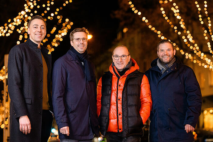 Vier Personen vor Weihnachtsbeleuchtung in Köln-Lindenthal.